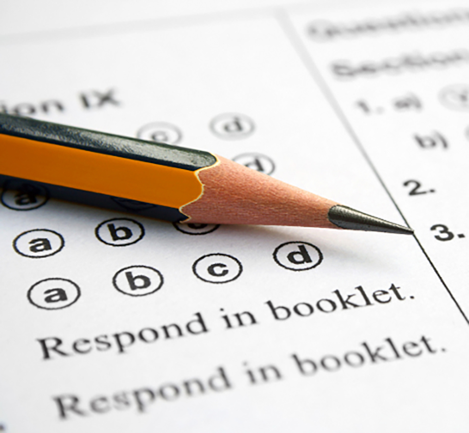 White test paper with multiple choice circles and a sharpened pencil on top of the paper