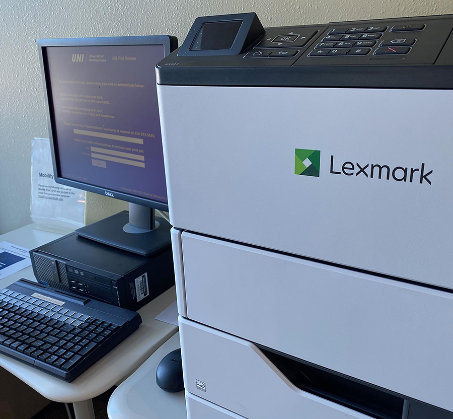 Printing station at UNI - Close up of computer with monitor to the left of a Lexmark printer